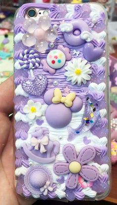 someone is holding up their phone case with purple and white decorations on the back,