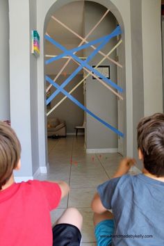 two young boys sitting on the floor in front of a door with tape taped to it