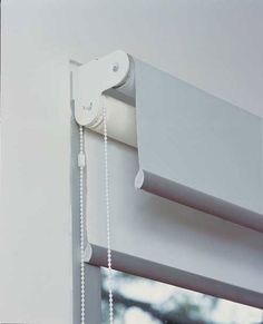 a white curtain with chain attached to it's side hanging from a window sill