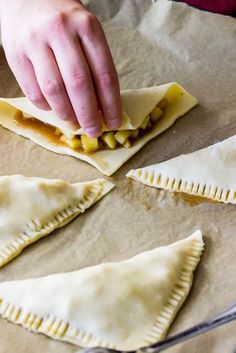 someone is making homemade empanadas on a baking sheet with their hands and fingers