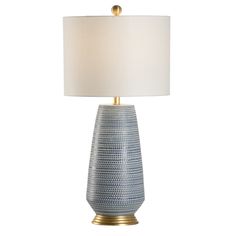 a table lamp with a white shade on it and a gold base around the lamp