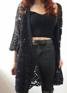 a woman with red hair wearing black clothing and holding her hand on her hip belt