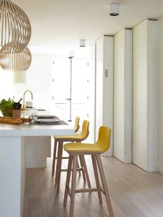 a kitchen with white counter tops and yellow chairs