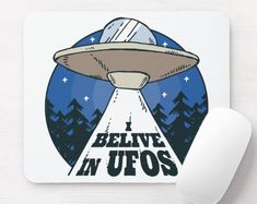 a mouse pad with an alien flying saucer in the sky and believe in ufos written on it