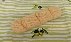 a crocheted object laying on top of a green and white striped cloth with olives