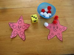 two pink stars next to some dices on a wooden table with a blue bowl