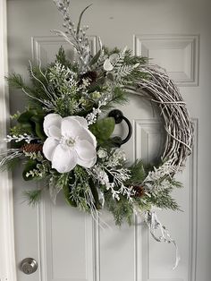 a wreath with white flowers and greenery hangs on the front door