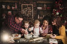 a group of people standing around a table with a baby and an adult cooking food