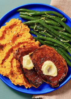 a blue plate topped with green beans and mashed potatoes