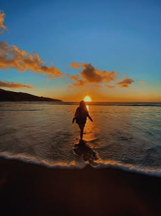 a person walking on the beach at sunset