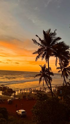 the sun is setting over an ocean with palm trees and people walking on the beach