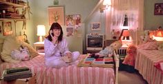 a woman sitting on top of a bed talking on a cell phone in a bedroom