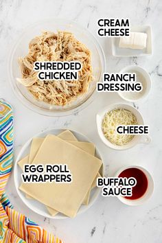 the ingredients needed to make an egg roll recipe on a white marble counter top, including shredded chicken, ranch dressing, eggs, cheese and buffalo sauce