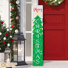 a merry christmas sign next to a red door with wreaths and garland on it