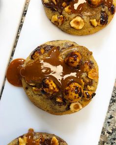 two cookies covered in caramel and nuts on top of a cutting board