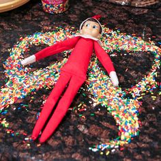 an elf laying on top of a table covered in sprinkles