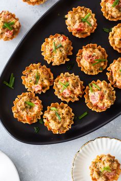 small appetizers are arranged on a black platter