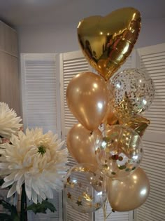 a vase filled with white flowers and gold balloons