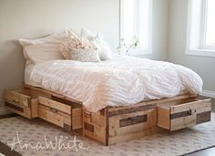 a bed with two drawers underneath it and a white comforter on top of the bed