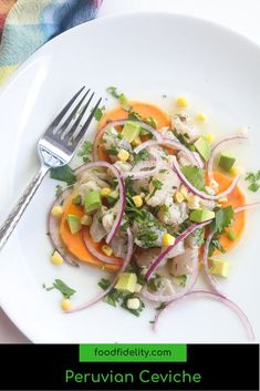 a white plate topped with vegetables and meat next to a fork on top of a table