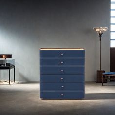 a blue dresser sitting next to a lamp in a room