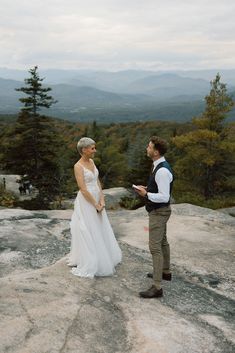 a bride and groom standing on top of a mountain