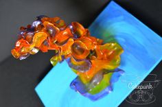 a glass vase filled with colorful flowers on top of a blue table