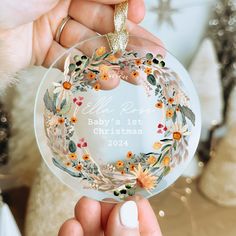 someone holding up a personalized ornament for their baby's first christmas