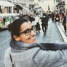 a woman taking a selfie in the middle of a busy street with people walking around