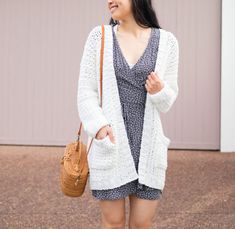 a woman wearing a white cardigan and holding a brown purse