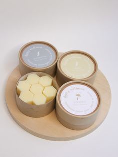 four different types of soaps sitting on a wooden platter with white and gray labels