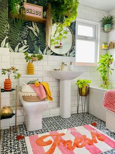 a bathroom with plants on the wall and a rug in front of the tub, sink, toilet and mirror