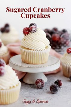 a cupcake with white frosting and cranberries is on a cake stand