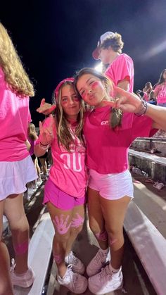 two girls in pink shirts and white shorts posing for the camera with their arms around each other