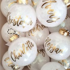 white and gold christmas ornaments in a box with the words merry written on one ornament