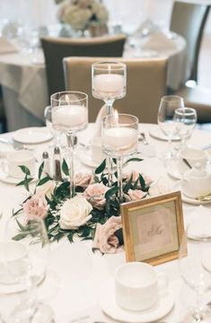 the table is set with candles, flowers and wine glasses for an elegant wedding reception