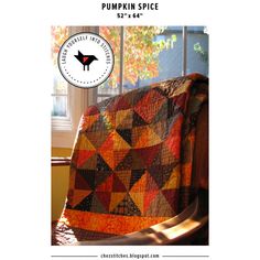 an orange and black quilt sitting on top of a wooden chair next to a window