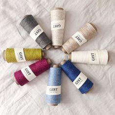 six spools of thread are arranged in a circle on a white sheet,