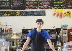 a man standing behind a counter in a coffee shop