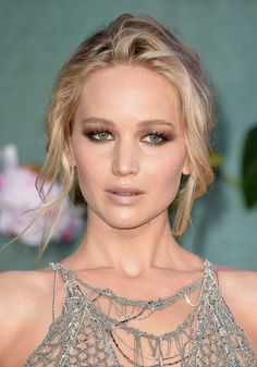 a close up of a person with blonde hair and eyeshade wearing a silver dress