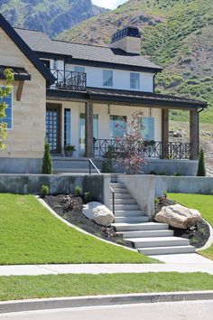 a house with steps leading up to the front door and landscaping on the lawn in front