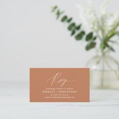 a close up of a business card on a table next to a vase with flowers