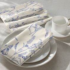 a white plate topped with two cups and saucers next to napkins on top of a table