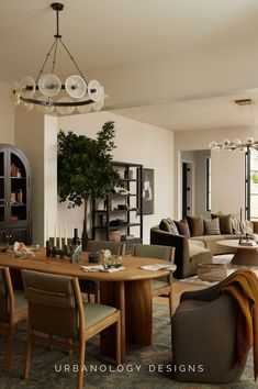 a living room filled with lots of furniture and a dining table surrounded by tall windows