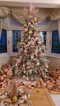 a decorated christmas tree in a living room with presents all around it and other decorations on the floor