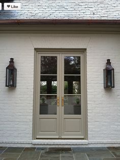 a white brick building with two doors and three lanterns on the side of each door