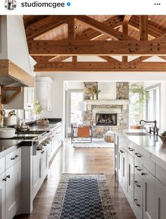 an open kitchen with white cabinets and wood beams on the ceiling, along with a blue area rug