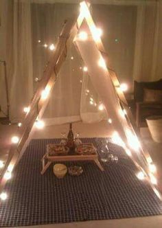 a teepee with lights on the floor and food in front of it at night