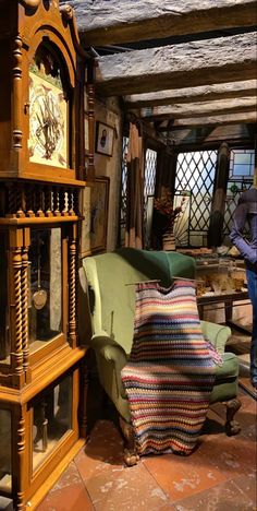 a living room filled with furniture next to a tall wooden clock mounted on the wall