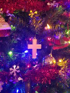 a cross ornament hanging from the top of a christmas tree